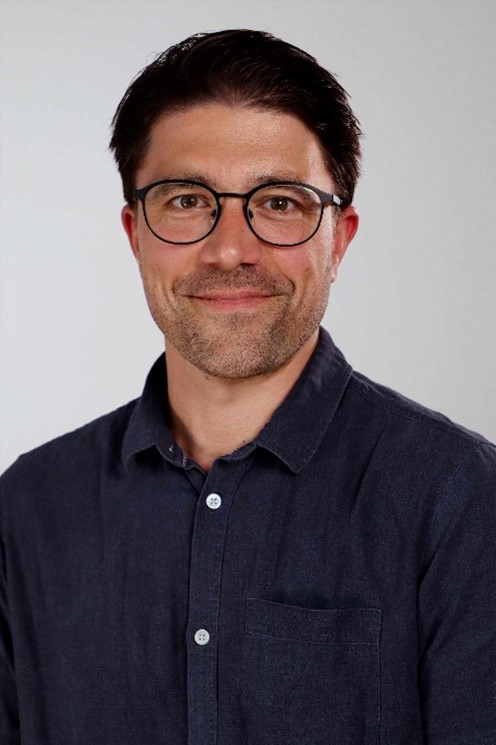 Personalefoto af smilende mand med briller og mørkt kort hår