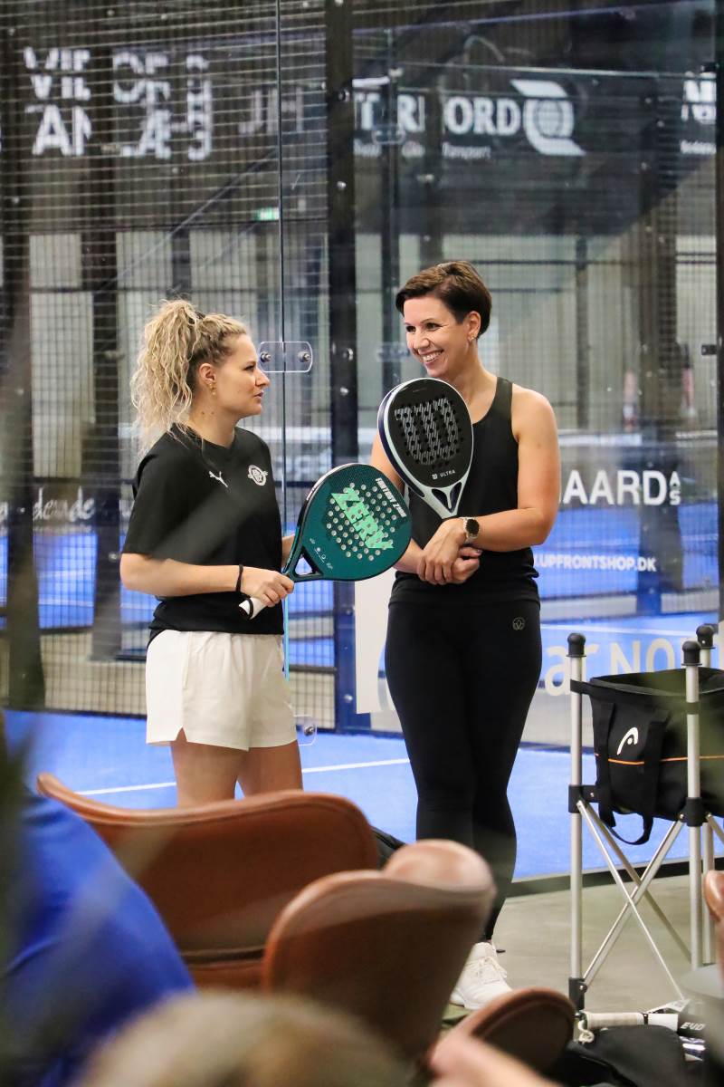 To kvinder står og snakker i mens de holder pause efter deres padel kamp på banerne ved VIborg padel