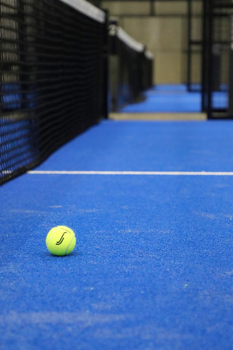 Gul Tennisbold ligger i det gyldnesnit på en blå padelbane