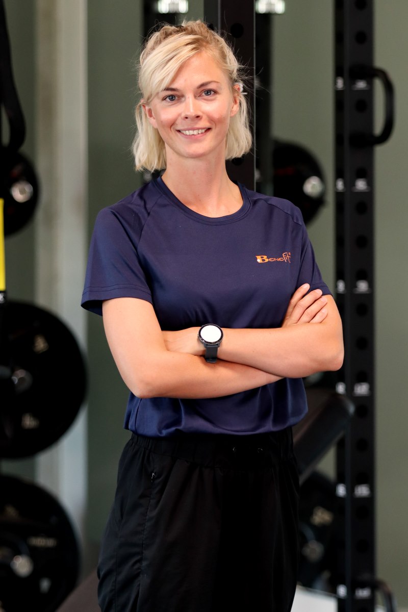 Personalefoto af smilende kvinde med lyst hår armene over kors og med træningsudstyr i baggrunden. Taget i Viborg